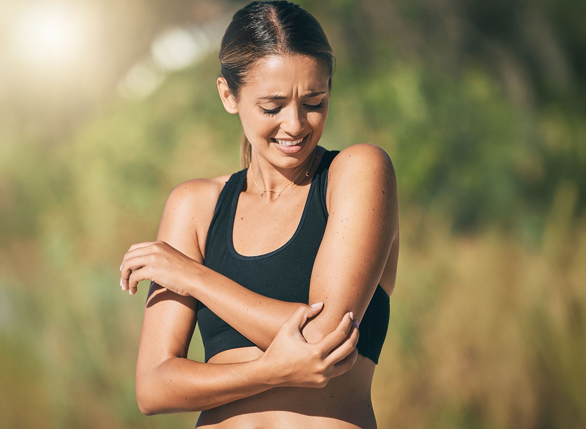 Fitness, woman and elbow in pain, injury or sports accident of runner suffering in joint ache outdoors. Athletic female holding painful area of muscle, inflammation or broken bone in discomfort