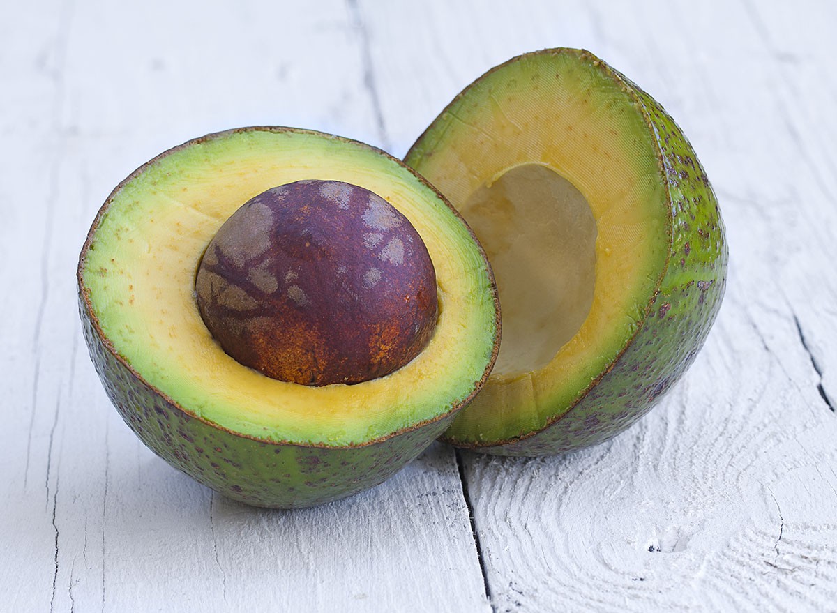 Oily big avocados cross section on white wooden table