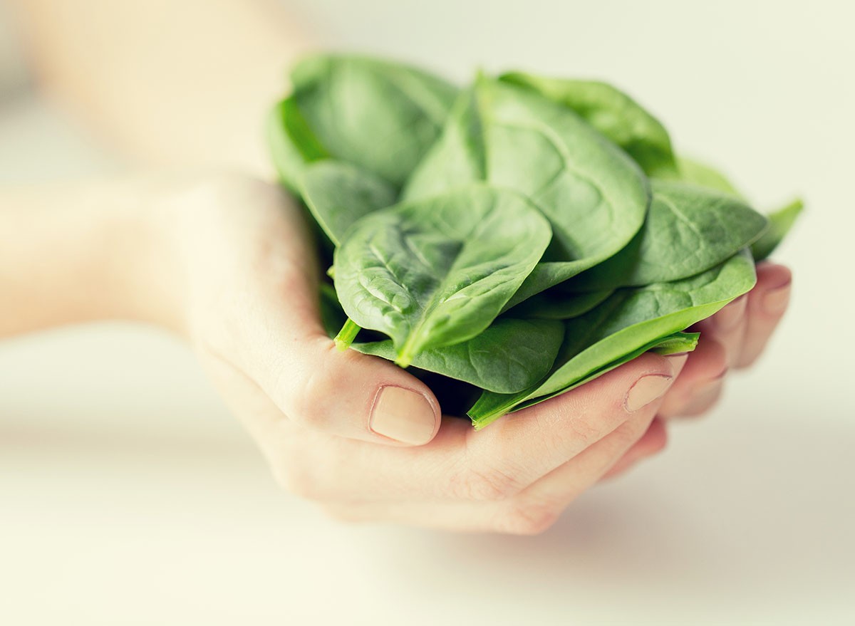 healthy eating, dieting, vegetarian food and people concept - close up of woman hands holding spinach at home