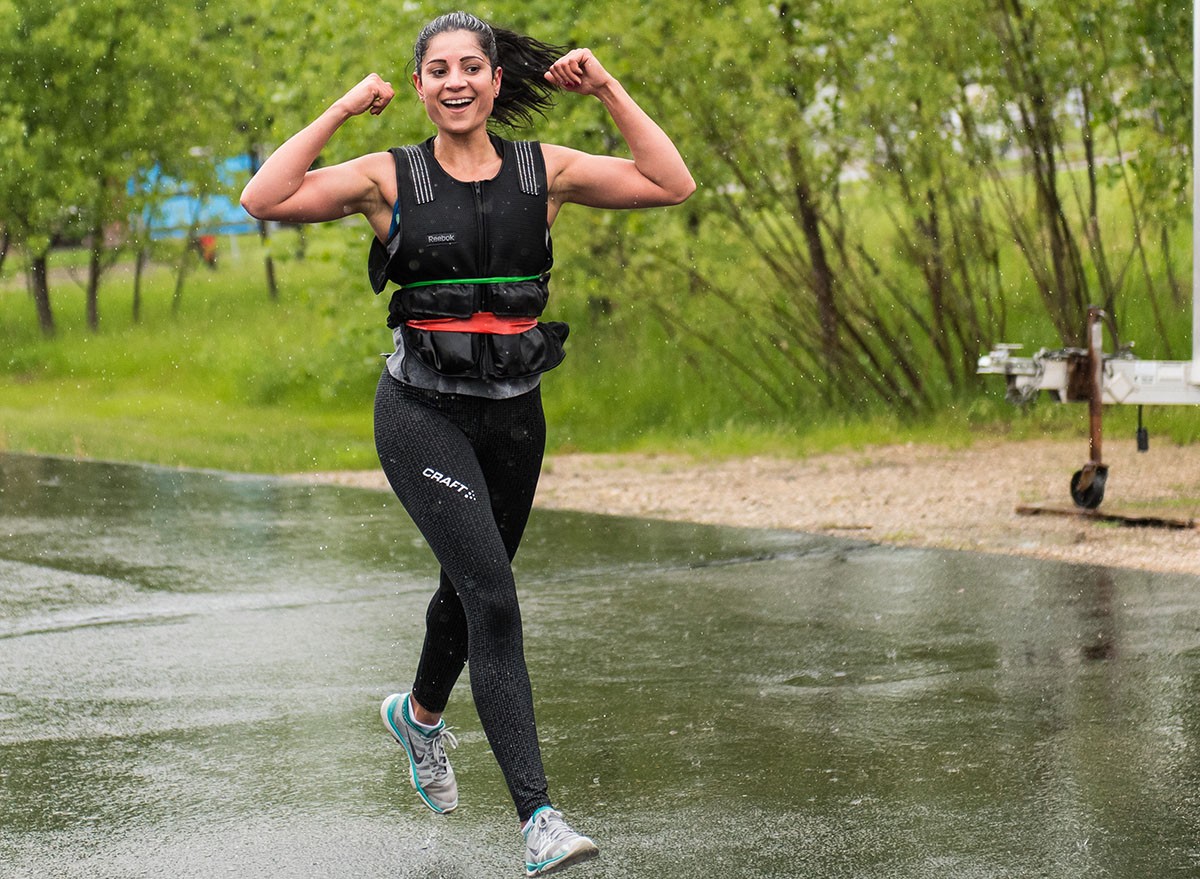 Happy woman running with a weighted vest
