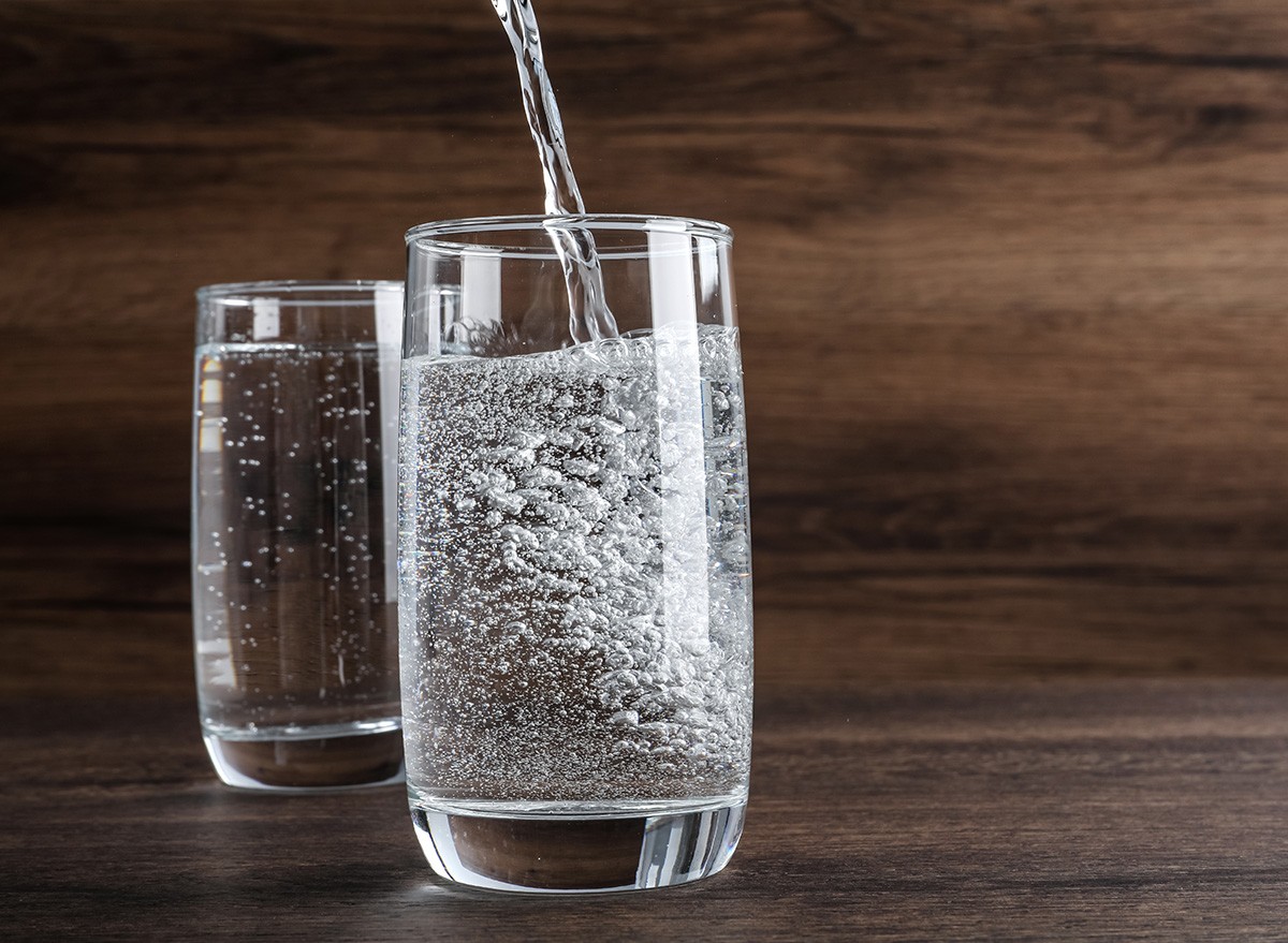 Pouring,Soda,Water,Into,Glass,On,Wooden,Table.