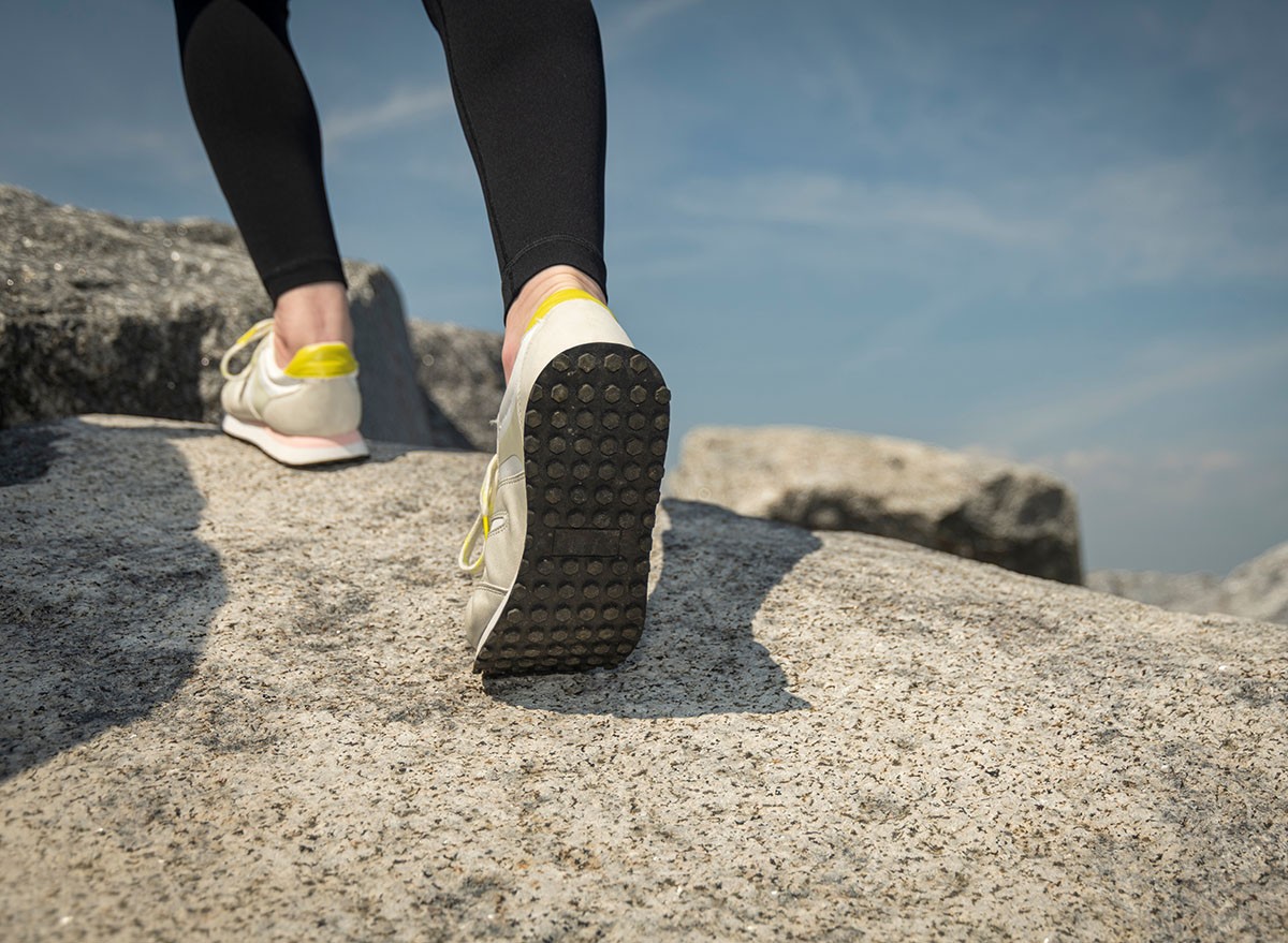 close up of walker climbing over rocks. Walking shoes, trainers.