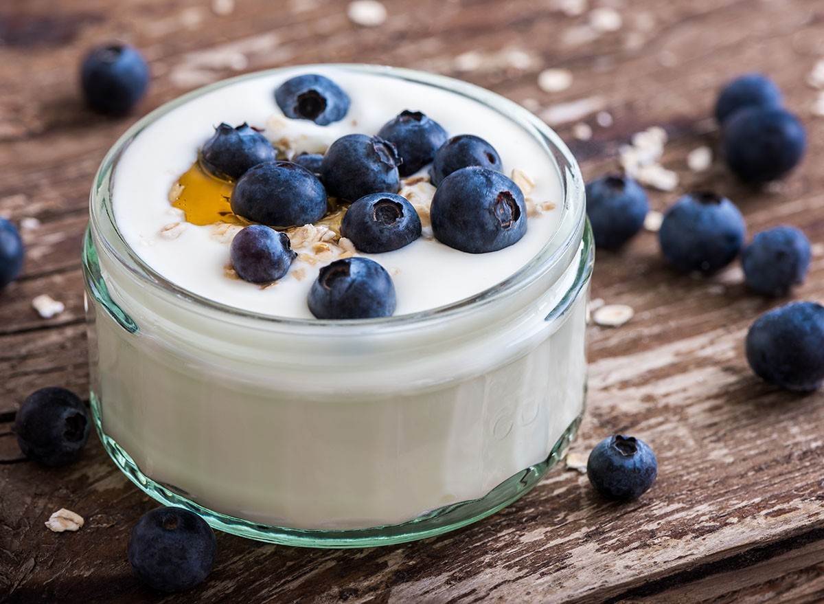 Serving of Yogurt with Whole Fresh Blueberries and Oatmeal on Old Rustic Wooden Table. Closeup Detail.