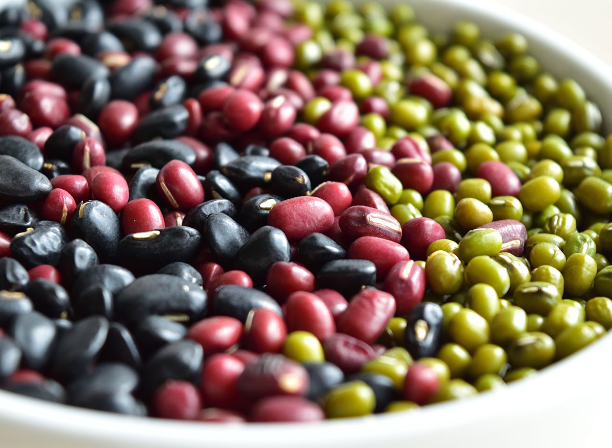 Top view of mixed beans : red kidney, black, mung in a white bowl background