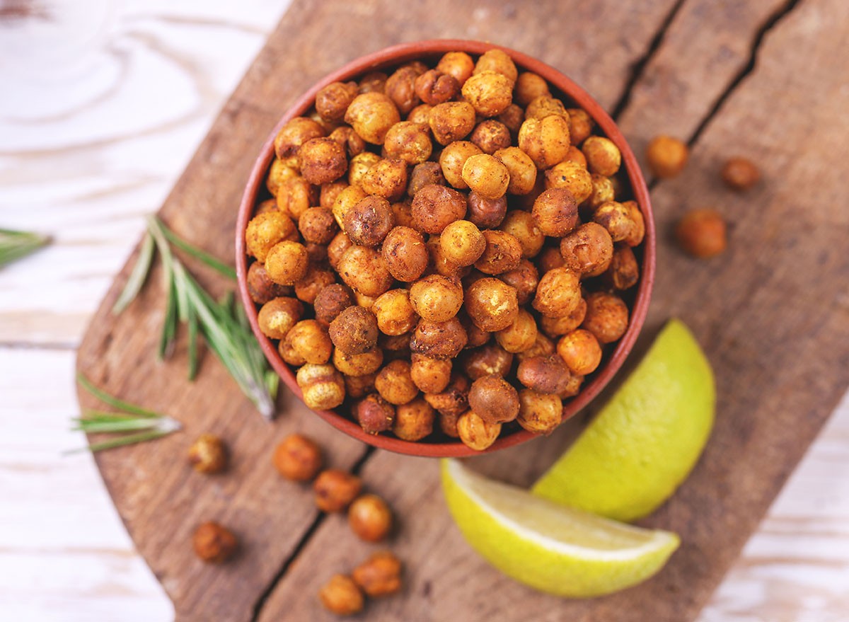 Traditional Indian cuisine. Roasted spicy chickpeas with lime and rosemary on rustic wooden background. Copyspace, top view.