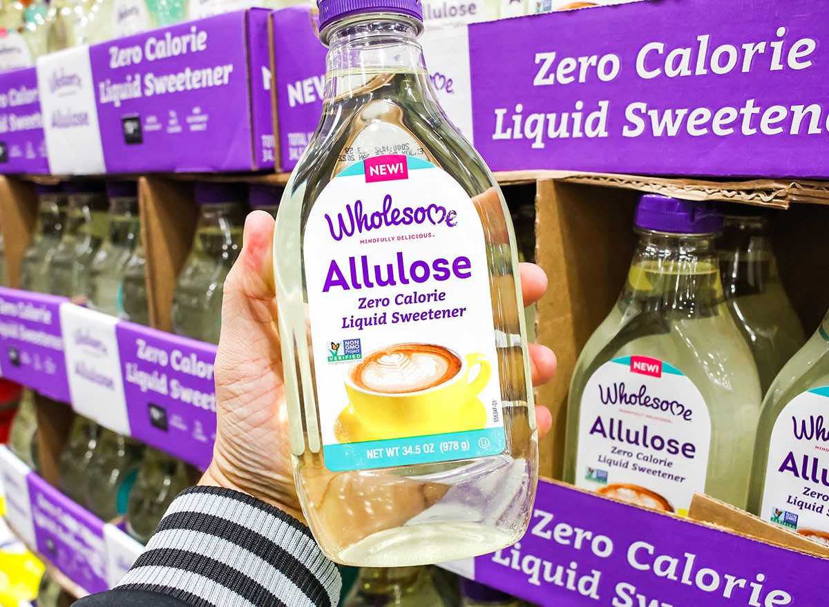 A view of a hand holding a bottle of Wholesome Allulose sweetener on display at a local big box grocery store.