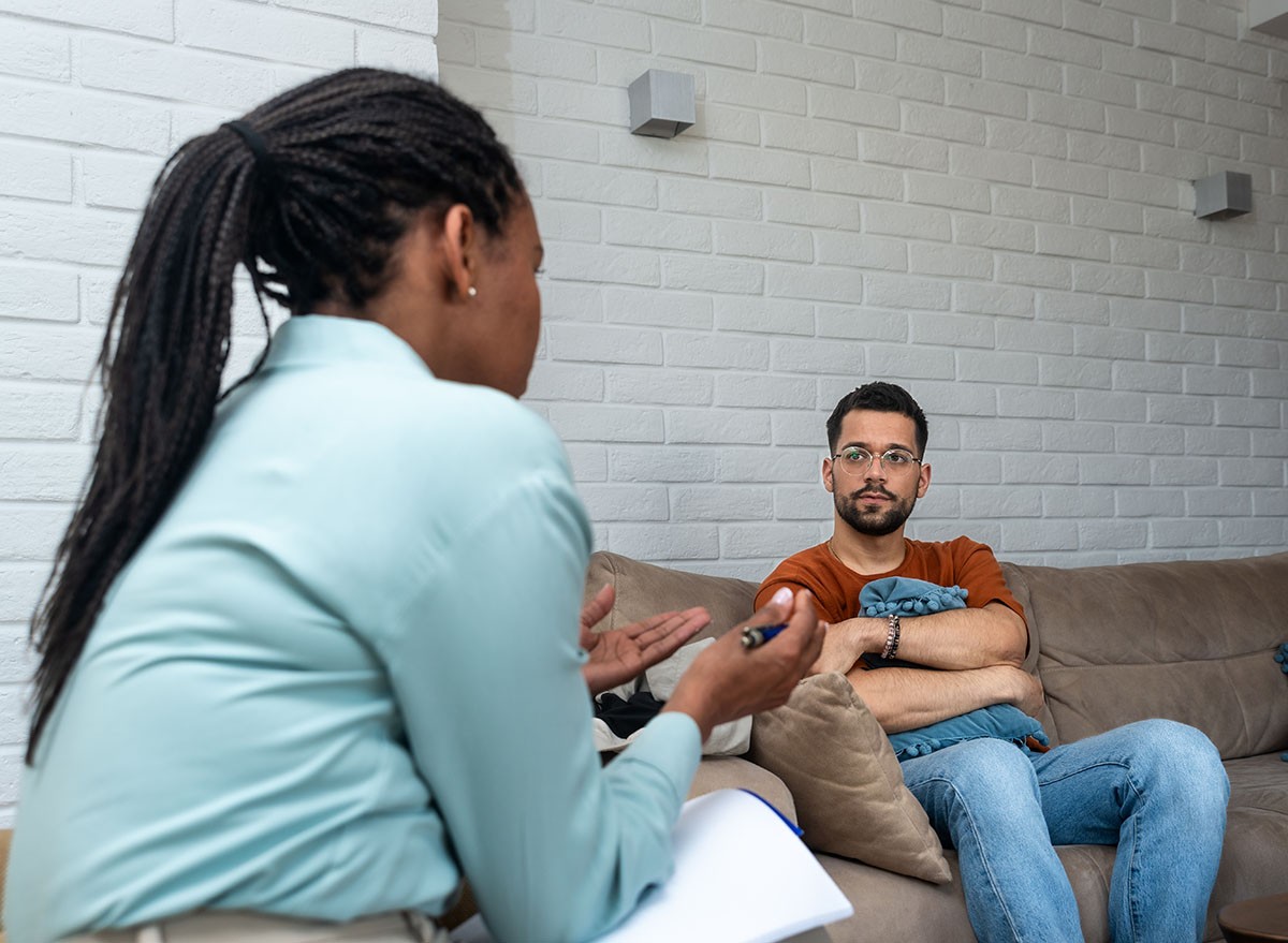 Young depressed man crying talking to mental health counselor during a session in the office. Stressed male at psychotherapy after divorce having emotional, therapist, therapy