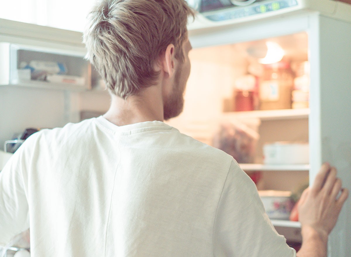 young man searching for food in fridge at home