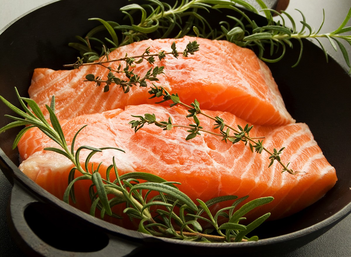 Frying pan with two salmon steaks and herbs, Shallow dof.