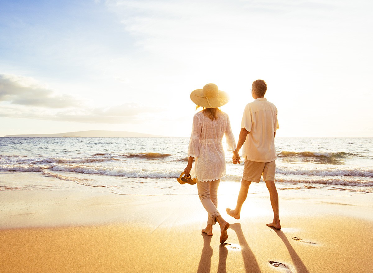 Happy Romantic Middle Aged Couple Enjoying Beautiful Sunset Walk on the Beach. Travel Vacation Retirement Lifestyle Concept