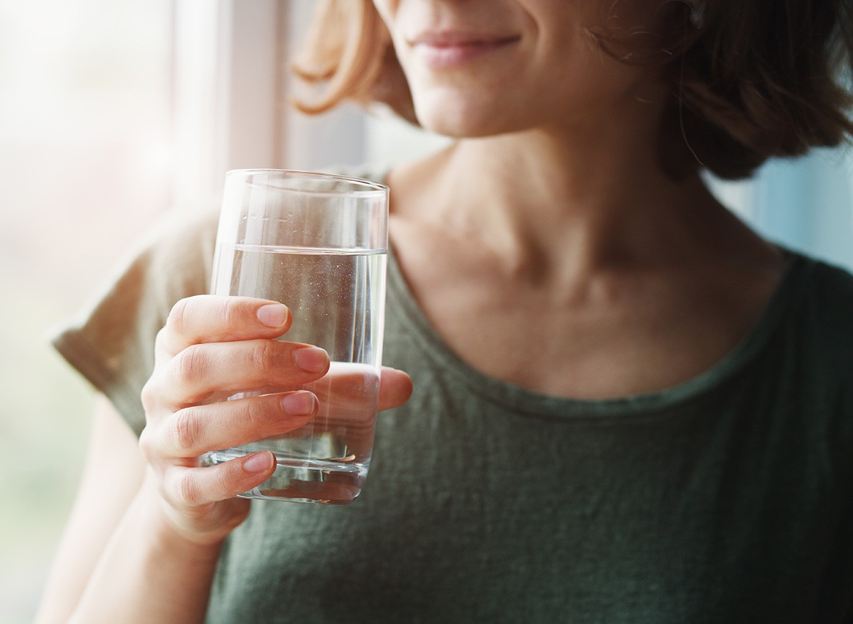 healthy beautiful young woman holding glass of water, drinking, morning, sunrise, sunset