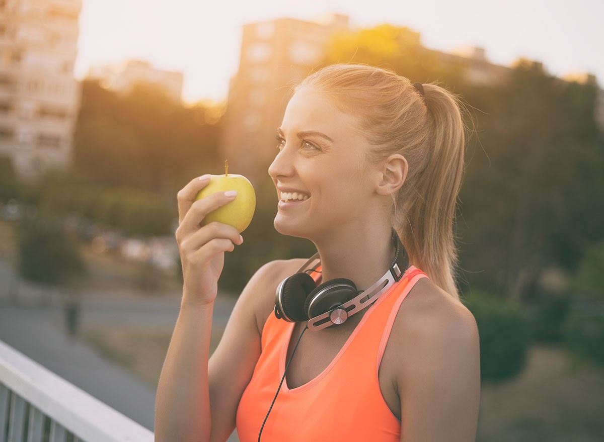 Beautiful sporty woman eating apple while resting from exercise.Healthy snack for fitness girl Image is intentionally toned.