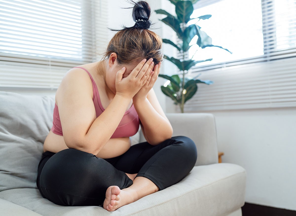 Obese Woman with fat upset bored of dieting Weight loss fail Fat diet and scale sad asian woman on weight scale at home weight control.
