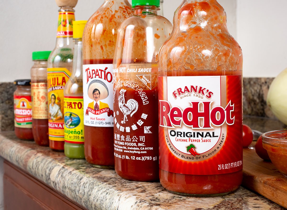 Los Angeles, California, United States - 06-09-2020:A view of a counter with a row of popular hot sauce bottles, featuring Frank's RedHot, Huy Fong Foods sriracha, Tapatio, El Pato, and Cholula. spice, spicy, sauce, pepper, peppers