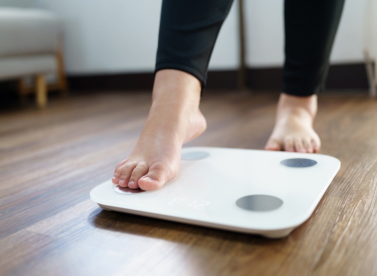 overweight woman on scale at home