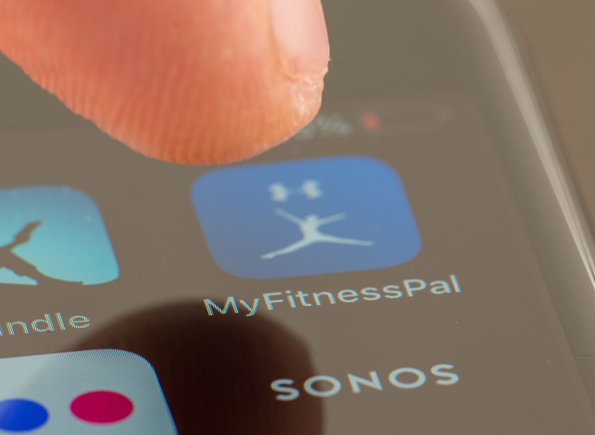 Person using Apple i-phone to press and access the MyFitnessPal app / application
